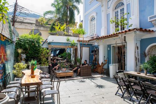 a group of people sitting on a patio with tables and chairs at Aurora Hostel Rio in Rio de Janeiro