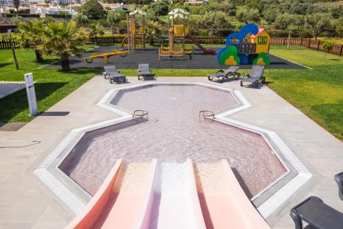 a pool in a park with chairs and a playground at Vila Gale Lagos in Lagos