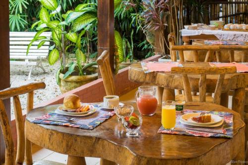 a wooden table with breakfast foods and drinks on it at Pousada Acquarela in Paraty