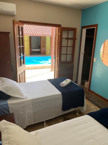 1 dormitorio con 2 camas y puerta a la piscina en Pousada Acquarela, en Paraty