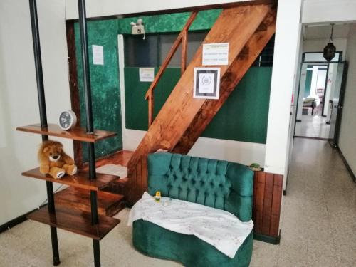 a living room with a green couch and a staircase at Casa Leon Guesthouse in San José