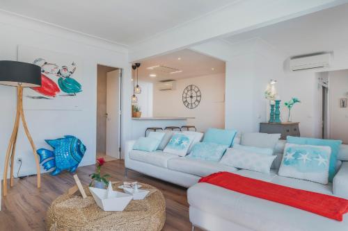 een woonkamer met een witte bank en blauwe kussens bij YupiHome Mariners Apartment in Alcudia