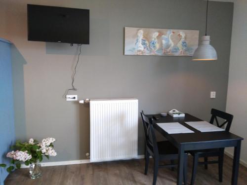 a dining room with a table and a tv on a wall at Langs De Maas in Boxmeer