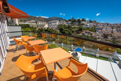 a balcony with tables and chairs and a view of a city at Hostal Casa Mercedes in Nerja