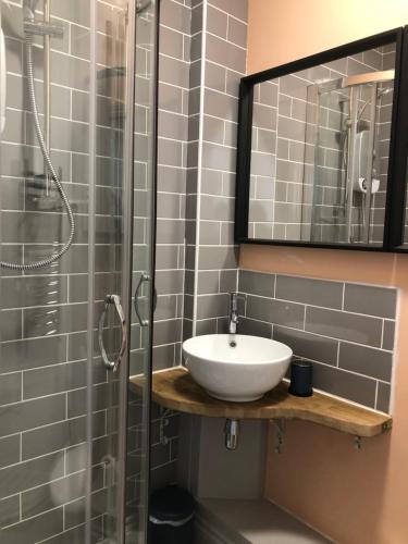 a bathroom with a sink and a shower with a mirror at High St. Hideout in Caernarfon