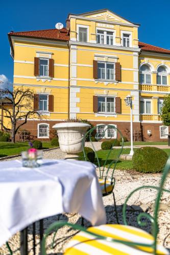 a yellow building with tables and chairs in front of it at Postwirt in Seeboden