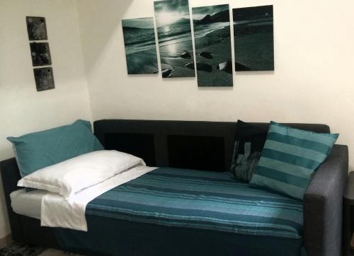 サレルノにあるCasa Vacanze EmaEleのベッドルーム1室(壁に4つの絵画が飾られたベッド1台付)