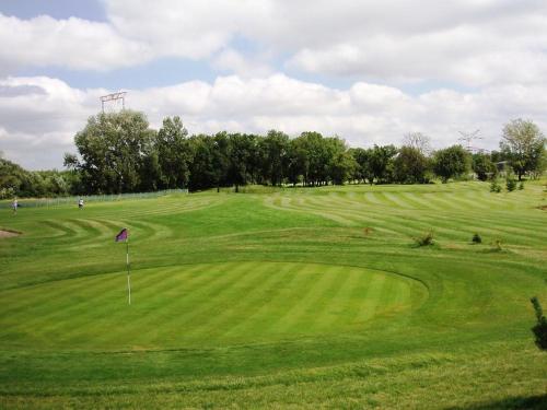 un campo de golf verde con una bandera en el medio en Kaštieľ AGATKA, en Chorvátský Grob