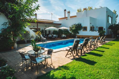 a patio with chairs and a table next to a pool at Casa de Cacela in Vila Nova De Cacela