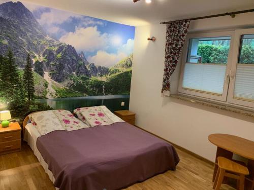 a bedroom with a bed with a mountain mural on the wall at Domek pod Maciejową in Rabka-Zdrój