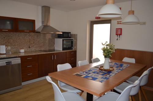a kitchen with a wooden table and white chairs at Domus Graciosa in Ponte de Lima