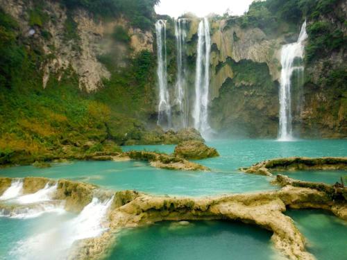 a waterfall in the middle of a pool of water at Kali Huasteca Posada in Ciudad Valles