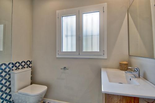 a bathroom with a toilet and a sink and a window at Llafranc Centre, Totally Refurbished in Llafranc