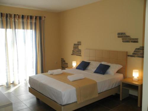 ein Schlafzimmer mit einem großen weißen Bett mit blauen Kissen in der Unterkunft Villa Cazala in Monemvasia