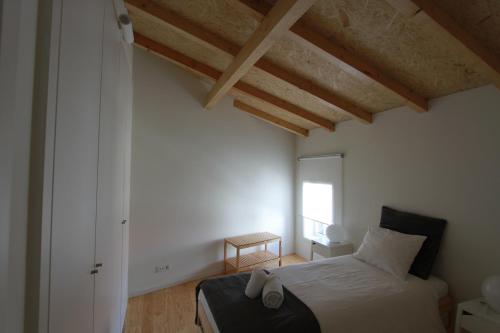 een slaapkamer met een bed in een kamer met houten plafonds bij Oporto City Cottage in Porto