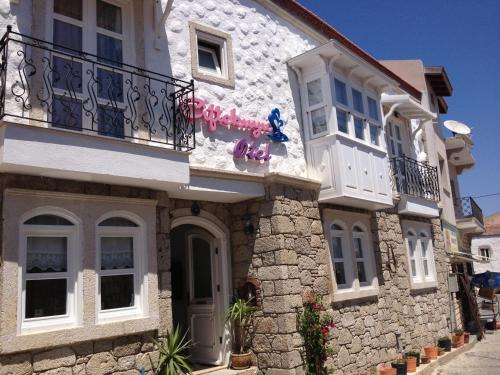 a white building with a balcony on a street at Ciftekuyu Hotel in Alaçatı