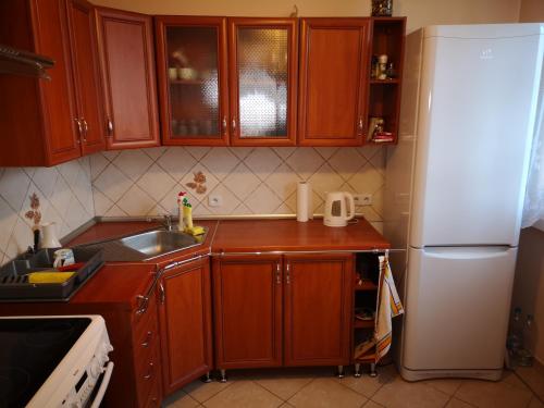 Apartament blisko Świeradowa في Mirsk: مطبخ بدولاب خشبي وثلاجة بيضاء