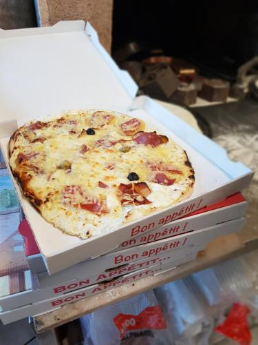 a pizza in a box sitting on top of two books at Hotel des voyageurs Chez Betty in Neussargues-Moissac