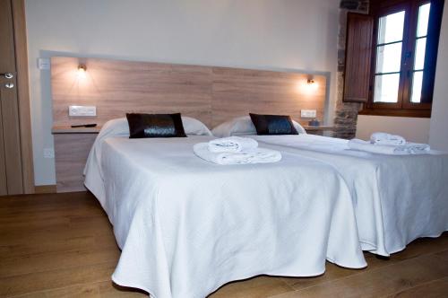 two beds in a hotel room with white sheets at PENSION SERRANO in Sarria