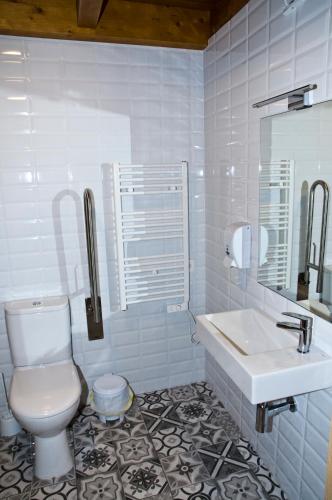 a white bathroom with a toilet and a sink at PENSION SERRANO in Sarria