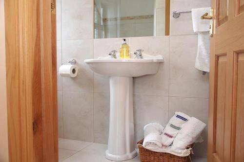 a white bathroom with a sink and a mirror at Bealaha House in Doonbeg