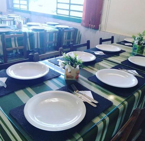 a table with white plates and napkins on it at Casa de Pedra Mineira in Canela