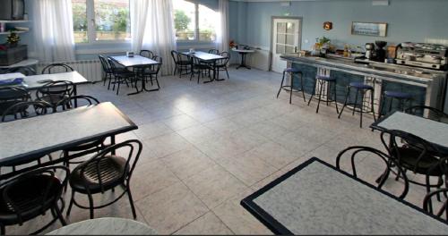 a dining room with tables and chairs and a kitchen at Pension Rocio in Ampuero