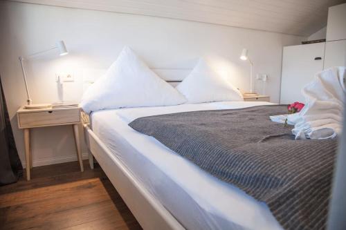 um quarto com uma cama grande com lençóis brancos e almofadas em Apartment JoniFee am Titisee em Titisee-Neustadt