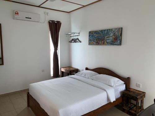 a bedroom with a bed with white sheets and a window at Hujung Kampung Estate in Pantai Cenang