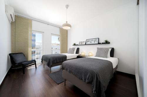 オリョンにあるBeautiful Modern Apartment in Olhão, Algarveのベッドルーム1室(ベッド2台、椅子、窓付)