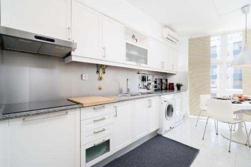 a kitchen with white cabinets and a washer and dryer at Beautiful Modern Apartment in Olhão, Algarve in Olhão
