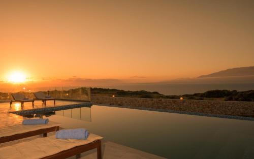a pool with a view of the ocean at sunset at DaLuz Villa in Koríthion