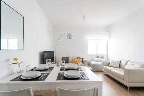 sala de estar blanca con mesa y sofá en TRIANA 3 Bedrooms & 2 bath Parking Included, en Sevilla