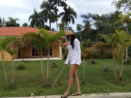 a woman in a hat is standing next to a palm tree at villa Clara in Los Róbalos