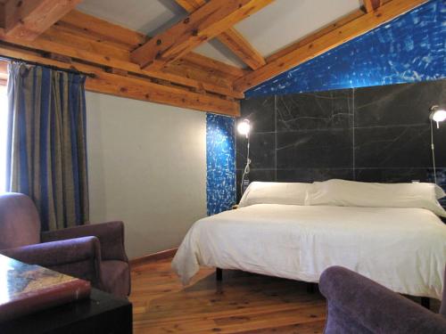 a bedroom with a large bed and two chairs at La Casa del Cura de Calatañazor in Calatañazor