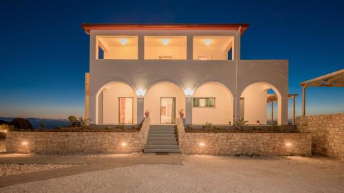 a large white house with lights in front of it at DaLuz Villa in Koríthion