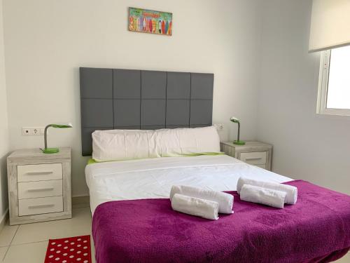 Un dormitorio con una cama grande con una manta morada. en Residencial El Pinet Beach, en La Marina