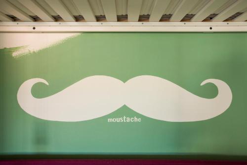 a green wall with a moustache sign on it at Mansardine Metropolitane in Brescia