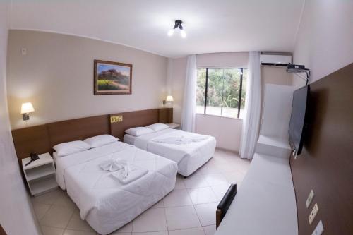 um quarto de hotel com duas camas e uma televisão em Hotel das Palmeiras em Teófilo Otoni