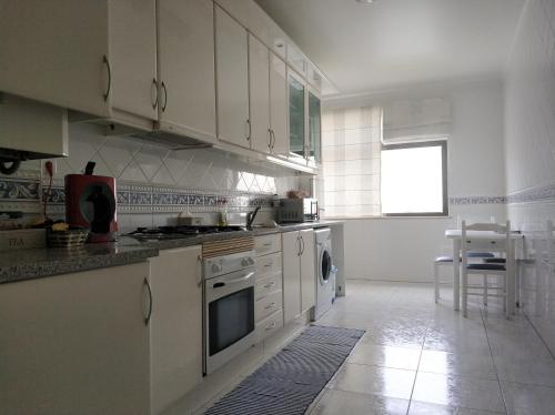 a kitchen with white cabinets and a stove top oven at Cidade da Praia in Figueira da Foz