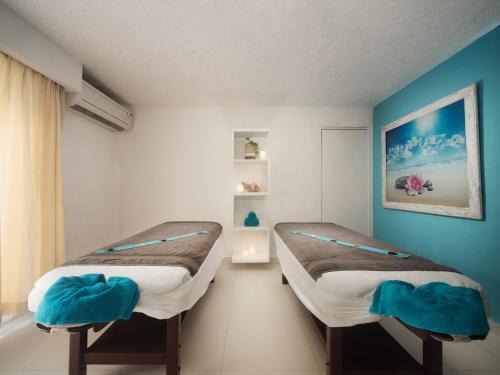 two beds in a room with blue walls at El Cid La Ceiba Beach in Cozumel