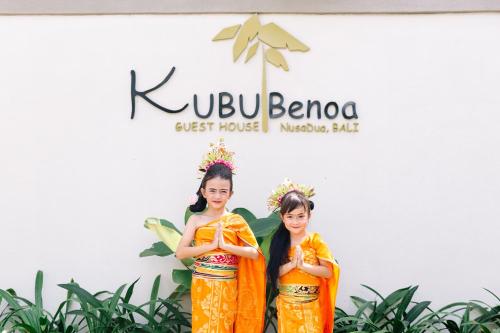 Due ragazze in uniforme arancione davanti a un cartello di Kubu Benoa Guest House a Nusa Dua