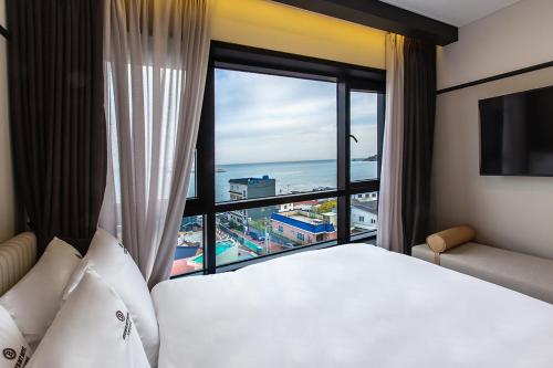 a hotel room with a bed and a large window at Brown Dot Gijang Yeonhwari in Busan