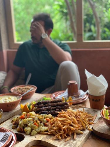 a man sitting at a table with a plate of food at ferme by Ikalimo in Ourika