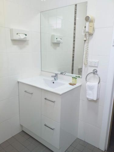 a white bathroom with a sink and a mirror at Bucketts Way Motel Gloucester in Gloucester