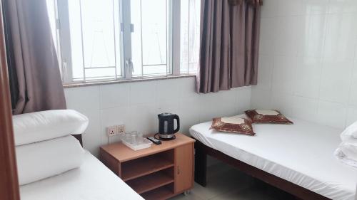 a small room with two beds and a window at Hung Fai Guest House in Hong Kong