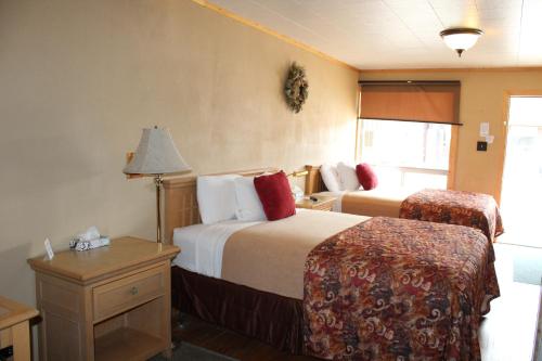 a hotel room with two beds and a lamp at Trail's End Motel Downtown Lewistown in Lewistown