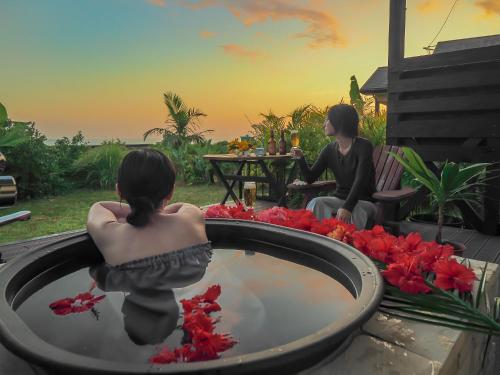 a woman sitting in a bath tub with a woman sitting at 森のフェアリー Cottage Morino Fairy All cotage with open-air bath with sea view or river view in Yakushima