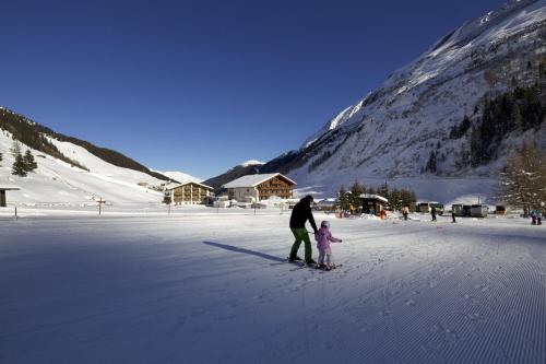 a man and a child on skis in the snow at Kinder- & Gletscherhotel Hintertuxerhof in Tux