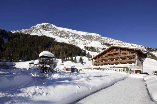 a ski lodge in the snow in front of a mountain at Kinder- & Gletscherhotel Hintertuxerhof in Tux